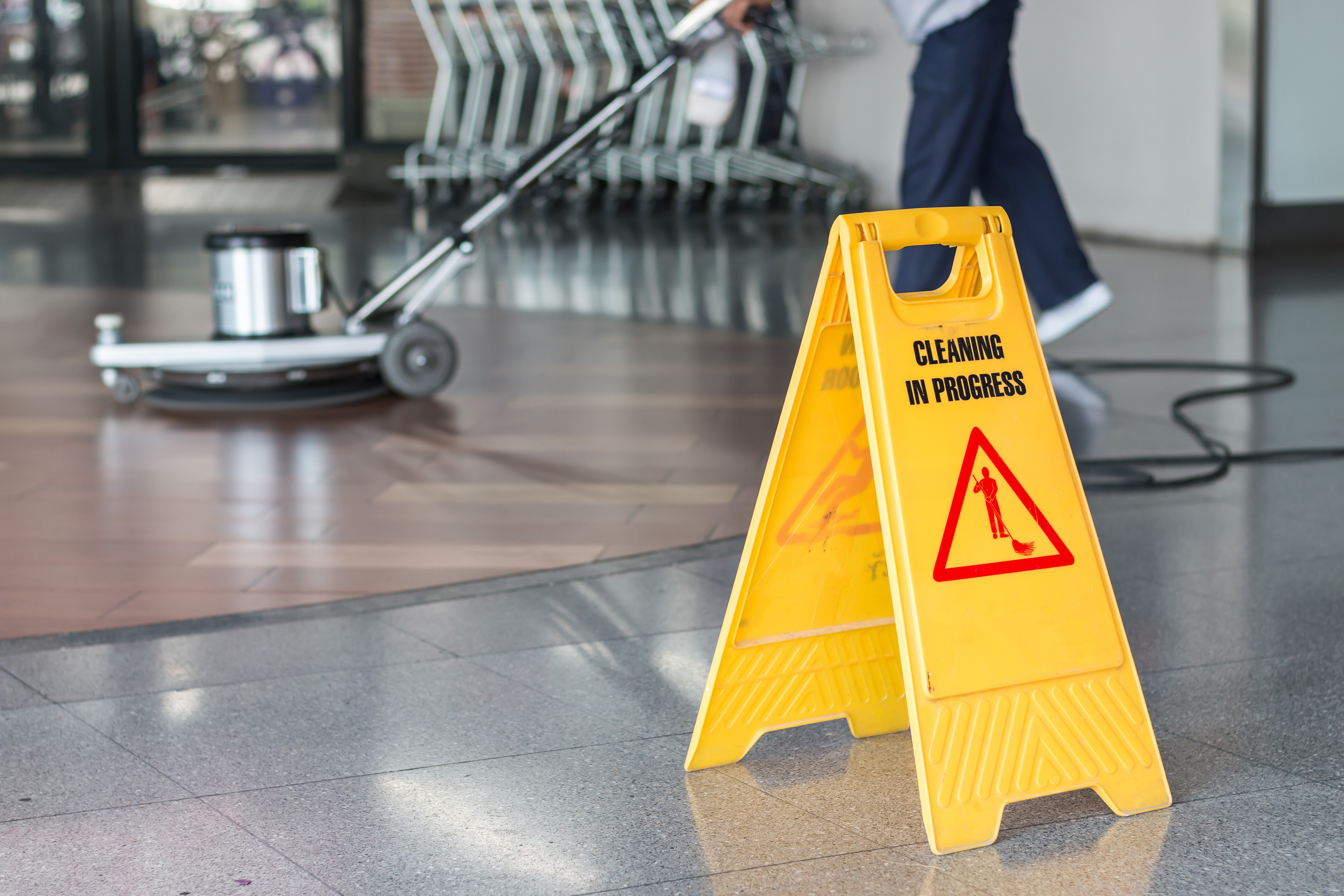 Yellow wet floor sign with "CLEANING IN PROGRESS" text and caution symbol in commercial space
